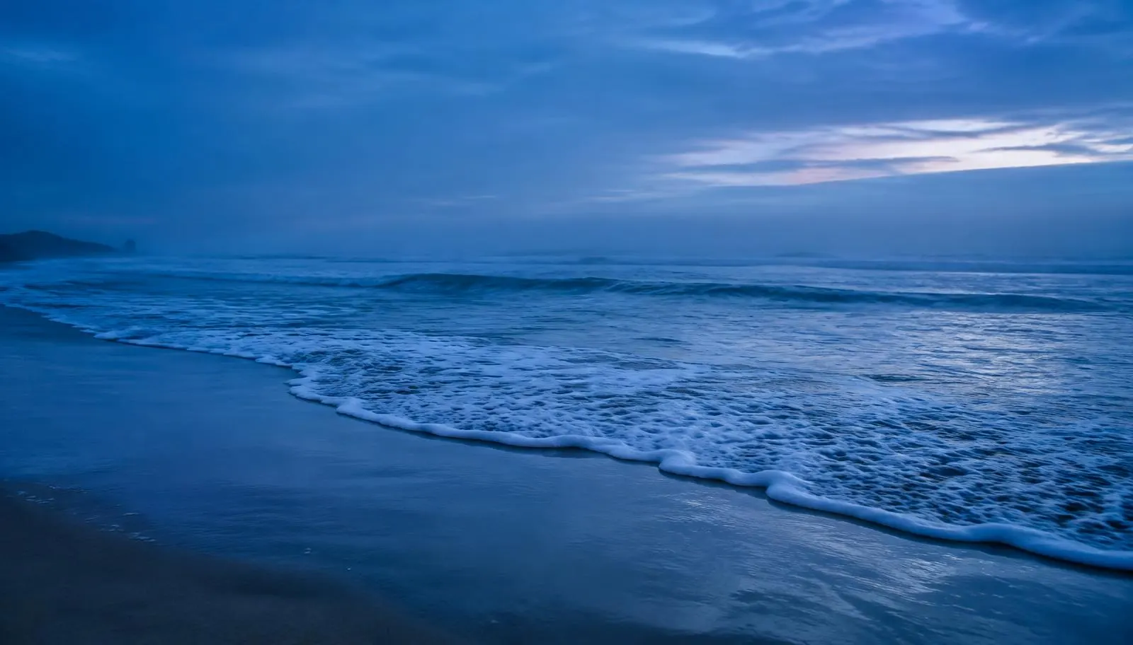 Ruhige Meereswellen am Strand zur blauen Stunde